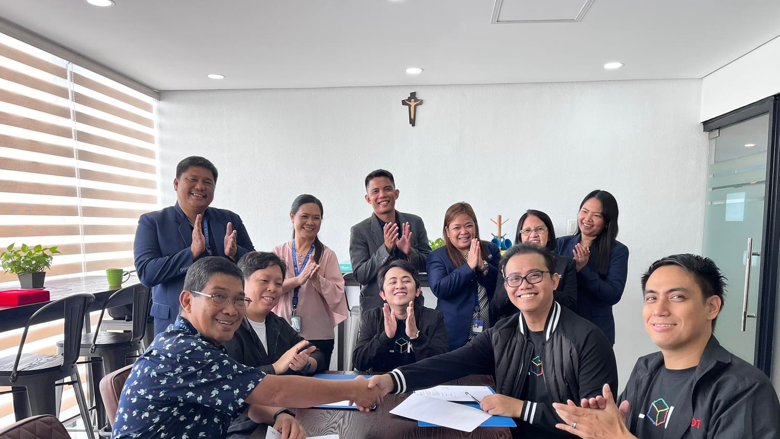 The BLOKC team and Adamson University representatives shaking hands at a partnership signing.