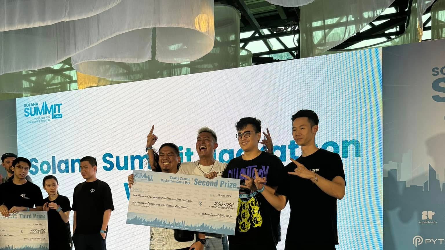 Winning teams celebrating on stage with oversized prize checks at the Solana Summit Hackathon Demo Day in Kuala Lumpur, backed by Superteam, Pyth, and Circle.
