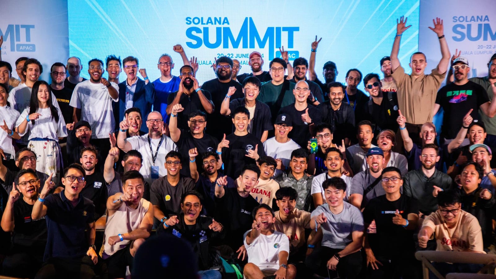 A large crowd of builders cheering and throwing their hands up under the Solana Summit APAC banner in Kuala Lumpur.