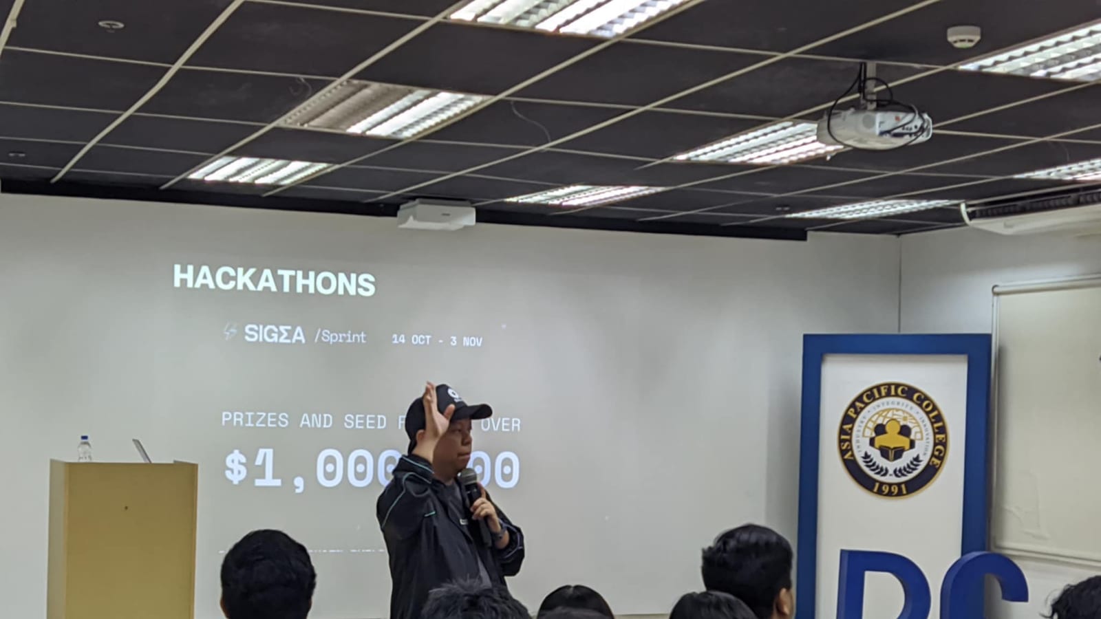 A speaker introducing the SIGMA Sprint hackathon and its prize pool to a seated audience at Asia Pacific College.