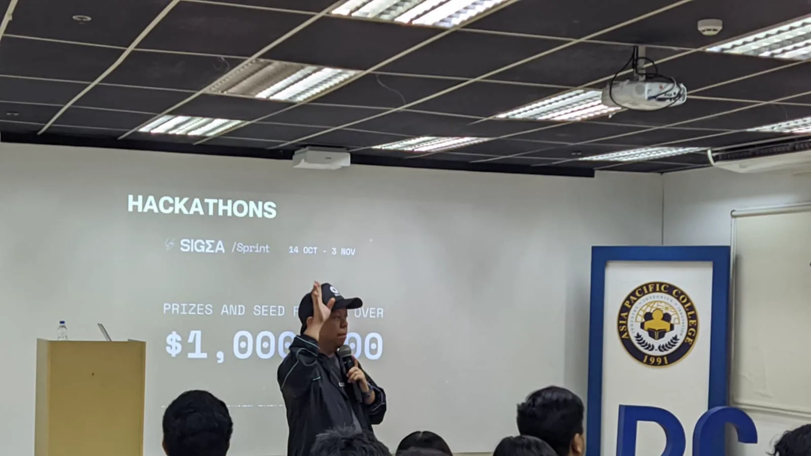 A speaker introducing the SIGMA Sprint hackathon and its prize pool to a seated audience at Asia Pacific College.