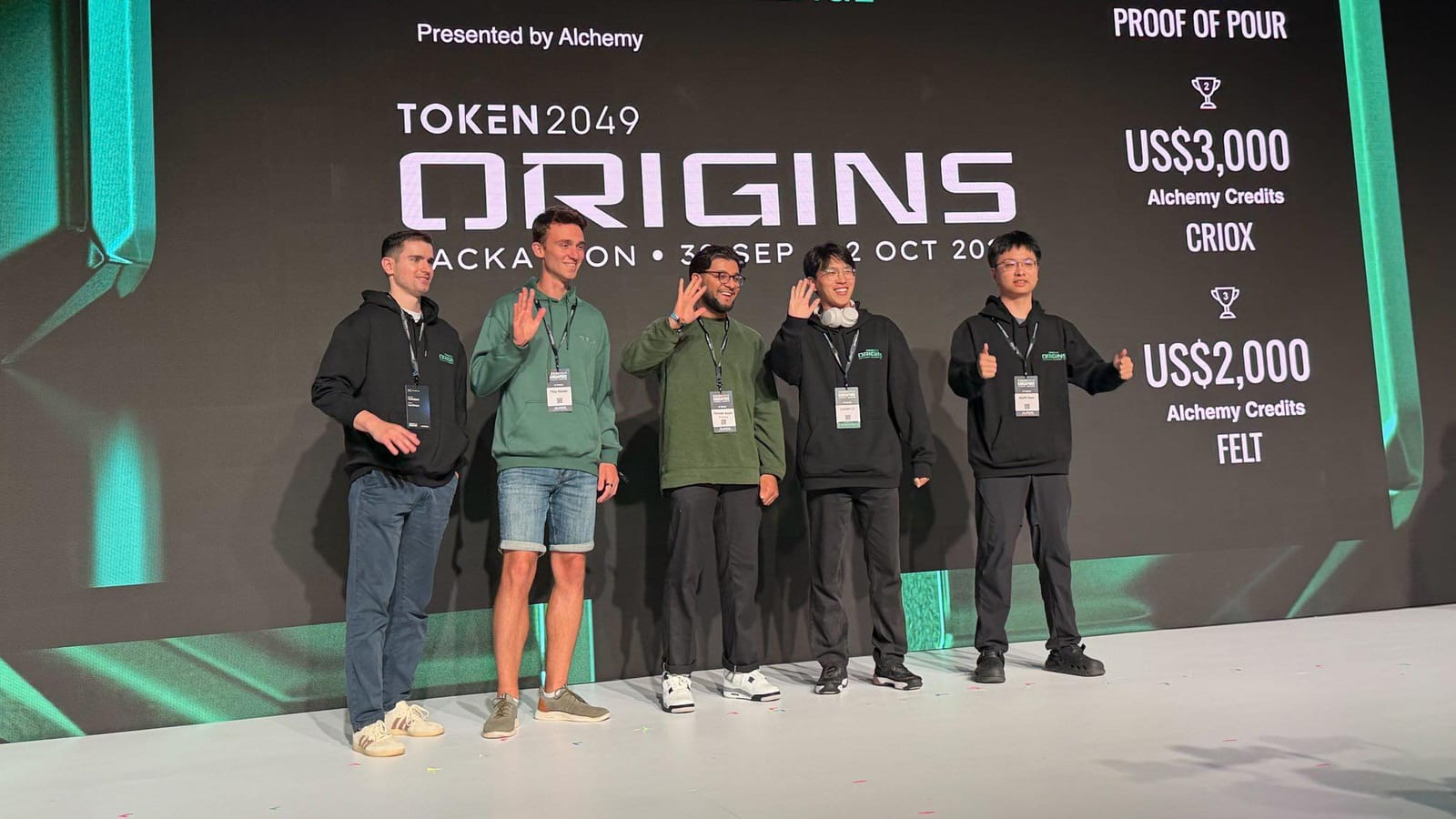 Five finalists waving on stage in front of the TOKEN2049 ORIGINS Real-World Smart Wallet Startup Challenge results presented by Alchemy.