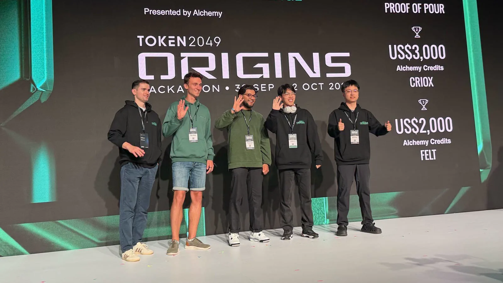 Five finalists waving on stage in front of the TOKEN2049 ORIGINS Real-World Smart Wallet Startup Challenge results presented by Alchemy.