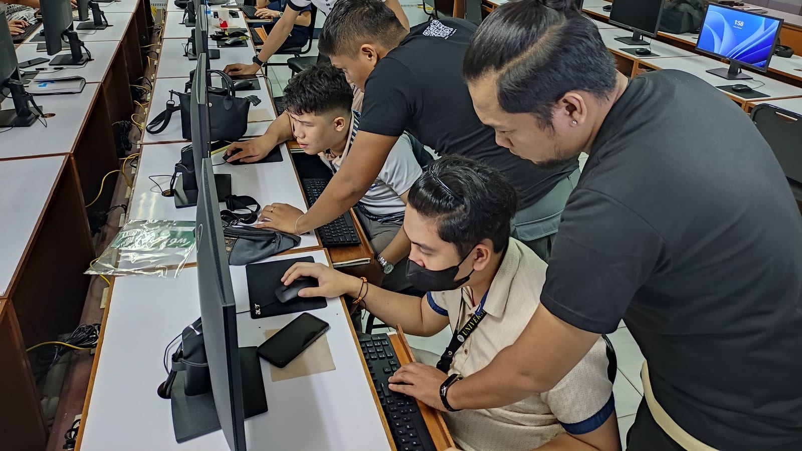 A BLOKC mentor leans in to help participants debug code at their lab workstations during a hands-on bootcamp session.