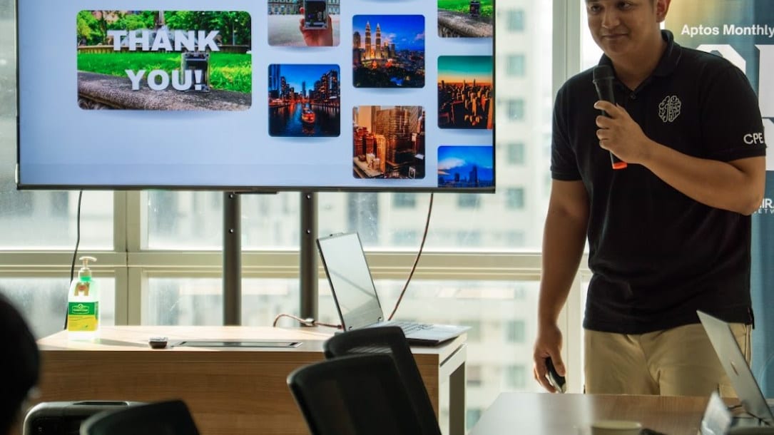 A builder wraps up a demo at an Aptos Monthly session with a thank-you slide on screen.